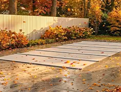 Geschlossene Rollladenabdeckung auf einem Pool, Herbstlaub auf der Terrasse
