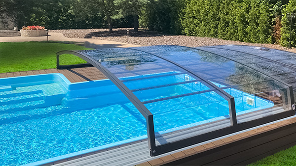 Schwimmbadüberdachung Aluna® Comfort R1 über einem privaten Außenpool