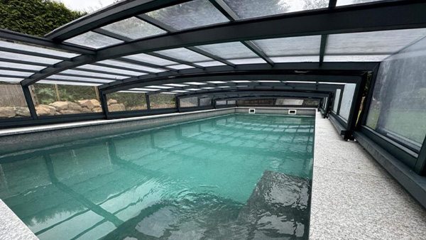 Flache Poolüberdachung Nero R1 in seitlicher Ansicht über einem Pool