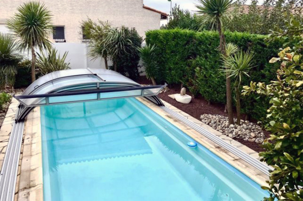 Aluna® Atlanta Poolüberdachung, flache Bauweise, geöffnet über einem blauen Pool