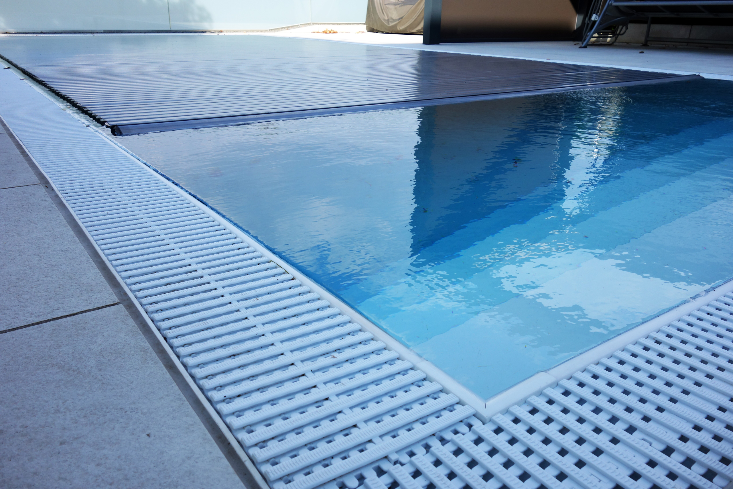 Detailansicht des Überlaufgitters und der Unterflurrolladen-Abdeckung eines Überlaufpools