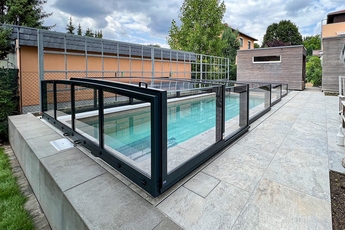 Flache Poolüberdachung Aluna Exclusive Line R1 mit transparenten Segmenten und dunklem Rahmen