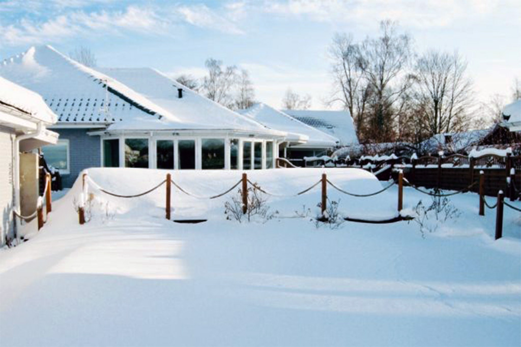 Poolüberdachung Aluna Atlanta unter einer dicken Schneedecke im Garten eines Hauses
