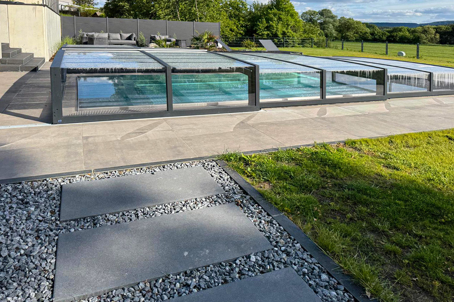 Edelstahlbecken mit transluzenter Poolüberdachung und Blick auf moderne Terrasse