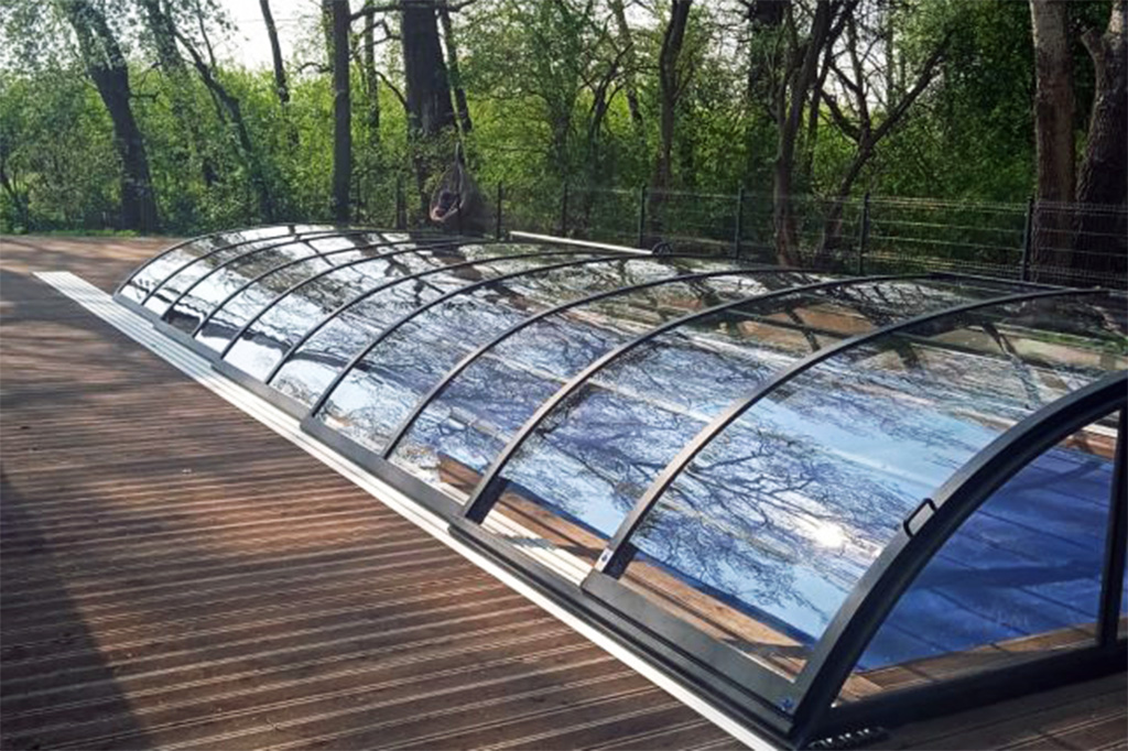 Detailansicht der flachen Poolüberdachung Aluna Atlanta mit transparenten Segmenten und dunklem Rahmen