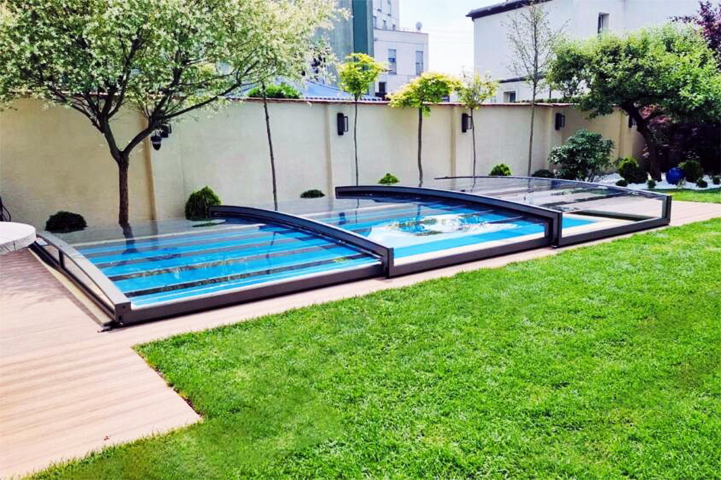 Flache Poolüberdachung Aluna Exclusive Line R1 mit transparenten Segmenten über blauem Pool im Garten