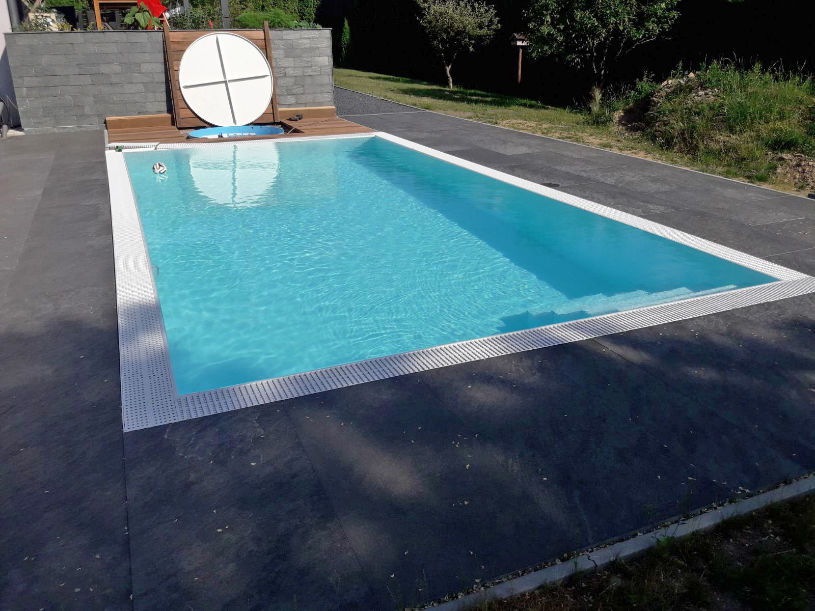 Weiße Überlaufrinne und dunkle Poolumrandung des Albixon G2 Polypropylen Pools mit Ecktreppe