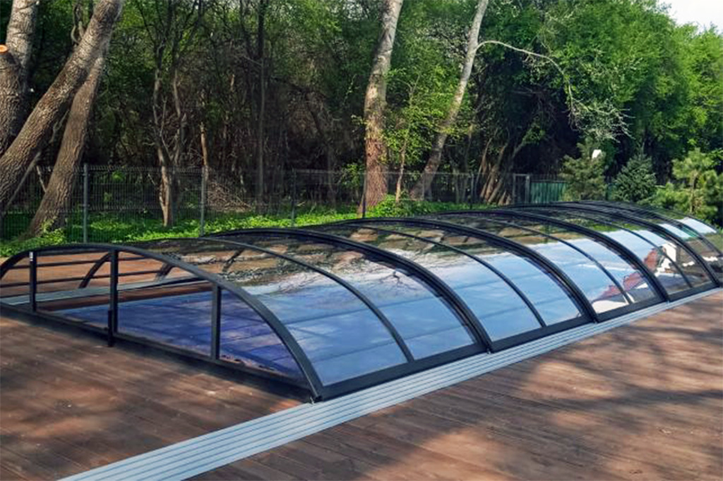 Flache Poolüberdachung Aluna Atlanta mit dunklem Rahmen und transparenten Segmenten auf Holzterrasse