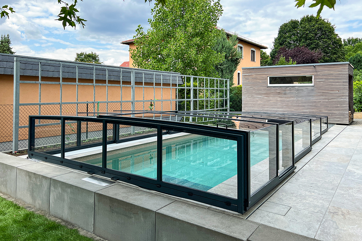 Flache Poolüberdachung Aluna Exclusive Line R1 mit anthrazitfarbenen Profilen über einem Pool