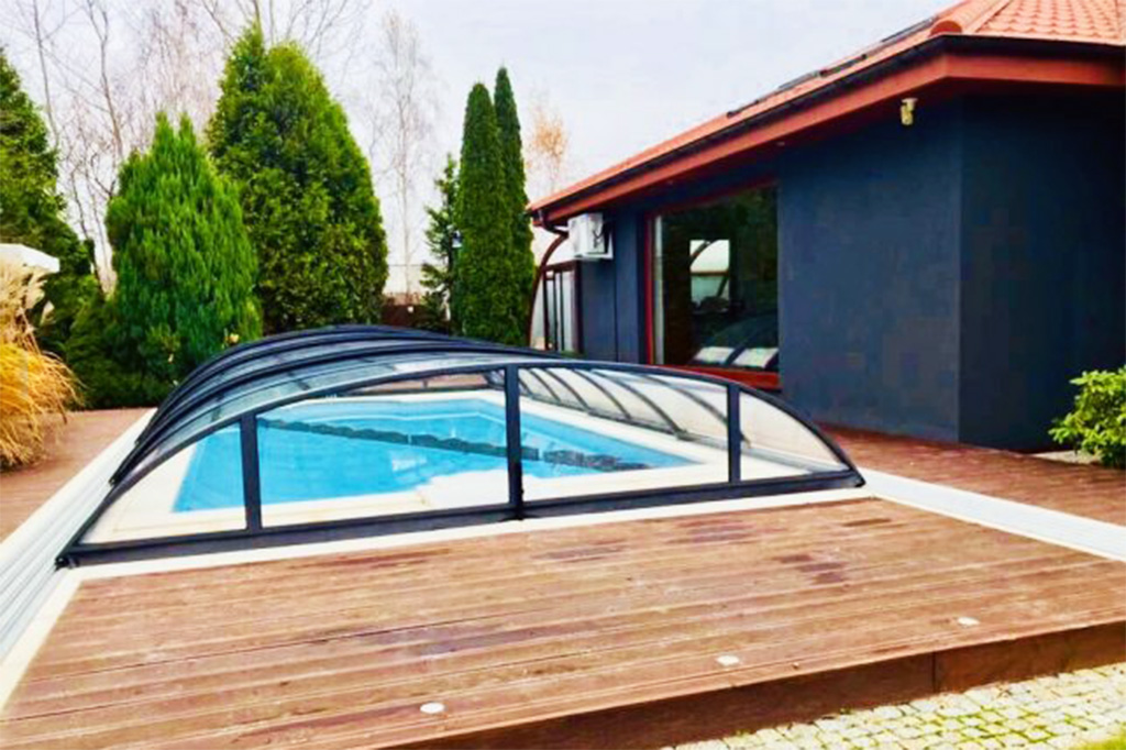 Flache Poolüberdachung Aluna Atlanta mit dunklem Rahmen über einem Pool auf Holzterrasse