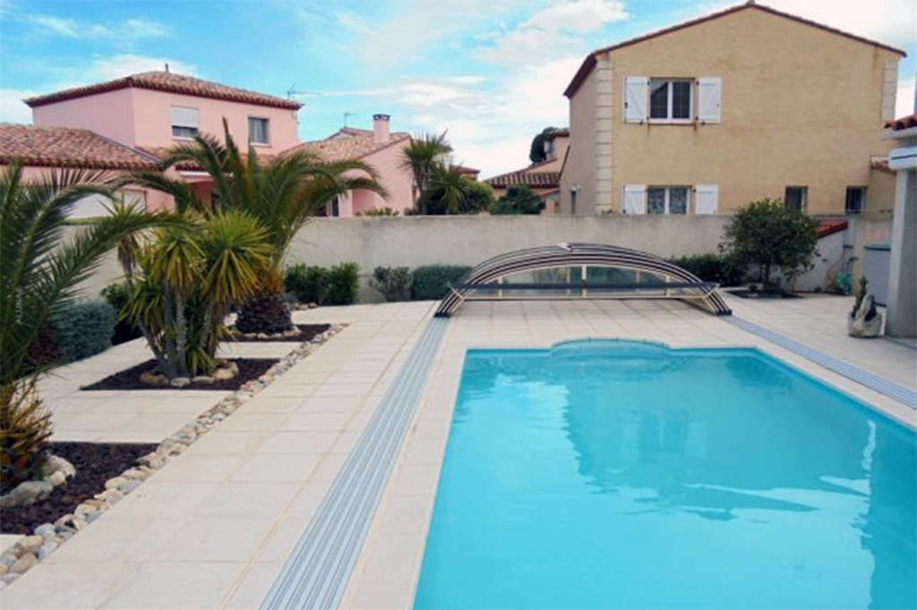 Flache Poolüberdachung Aluna® Atlanta halb geöffnet über dem Pool mit blauer Folie