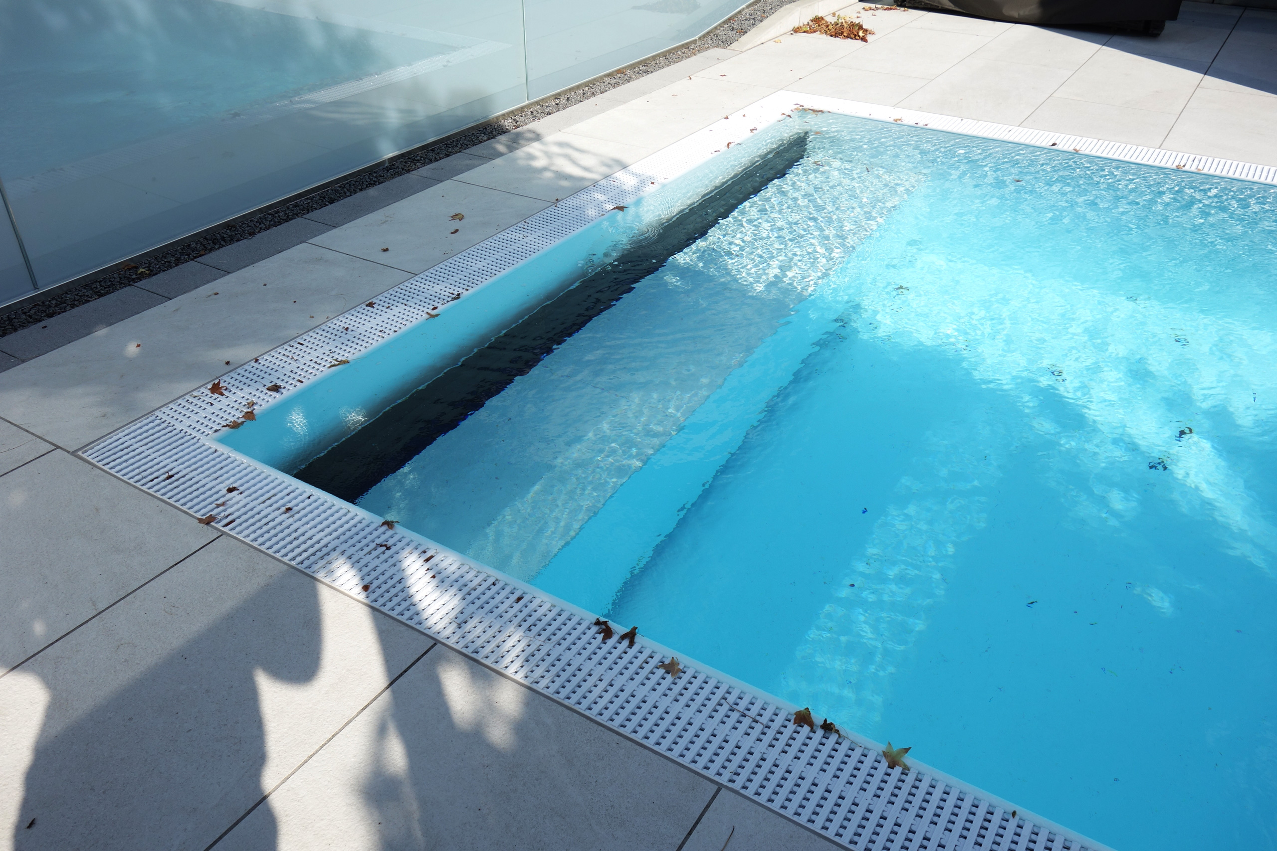 Detailansicht des Überlaufpools mit gerader Treppe, Podest und den weißen Überlaufrinnen